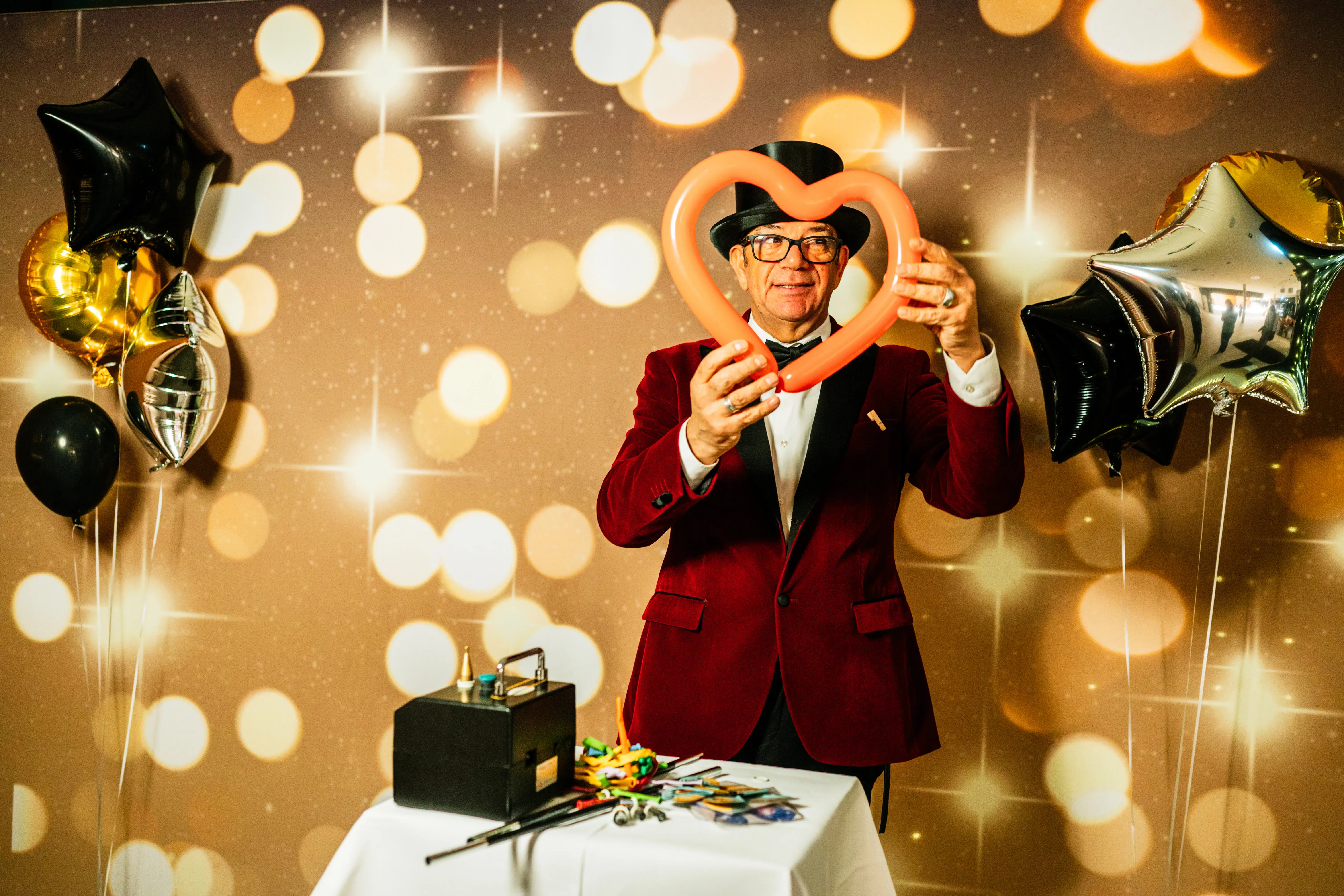 Ein Mann in rotem Anzug bastelt Figuren aus langen Luftballons