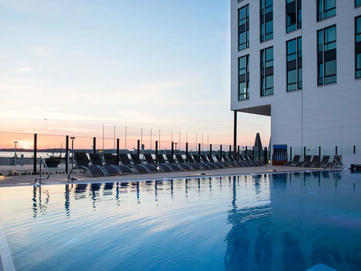 Ein Pool mit Stühlen und einem Gebäude im Hintergrund.