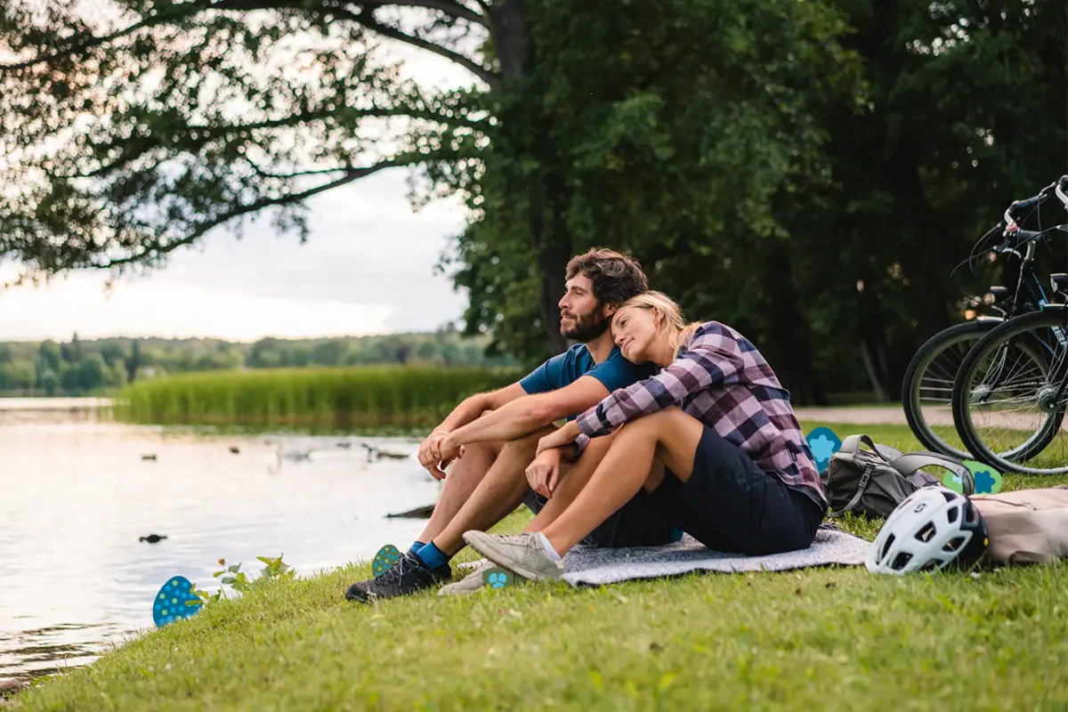 Ein Mann und eine Frau sitzen auf einer Decke am See.