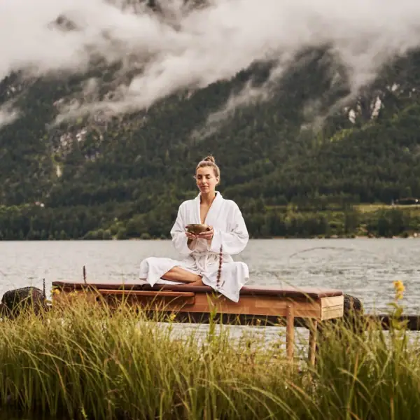 Eine Frau sitzt auf einer Bank am See.