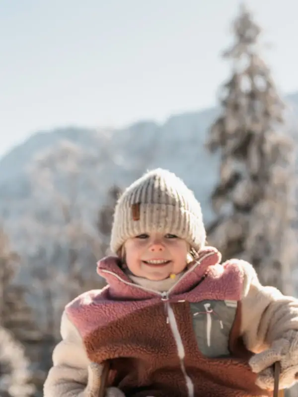 Ein Kind sitzt auf einem Schlitten im Schnee.