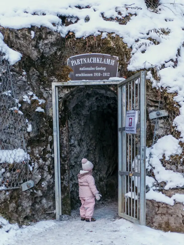 Ein kleines Kind steht im Eingang zur Partnachklamm im Familienurlaub in Bayern.