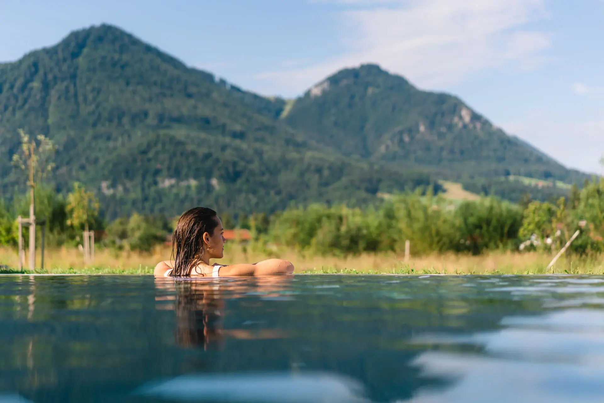 Eine Frau im Pool mit Bergen im Hintergrund