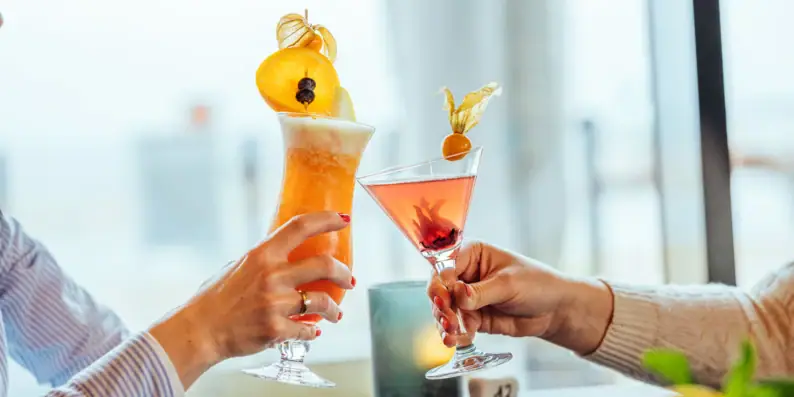 Hände halten Gläser mit Cocktails.