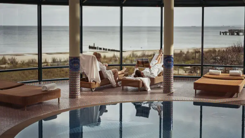 Ein Paar in weißen Bademänteln am Pool.