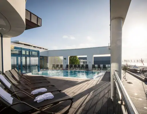 Wellnessbereich im aja Grömitz Pool mit Liegestühlen und Deck im Freien