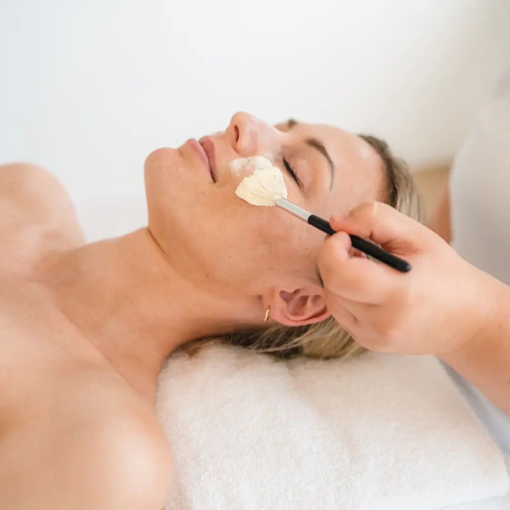 Eine Frau liegt mit einem Pinsel im Gesicht.