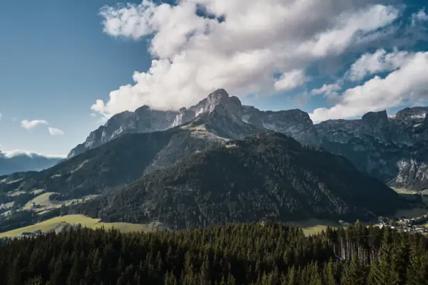 Ein Berg mit Bäumen und Wolken.