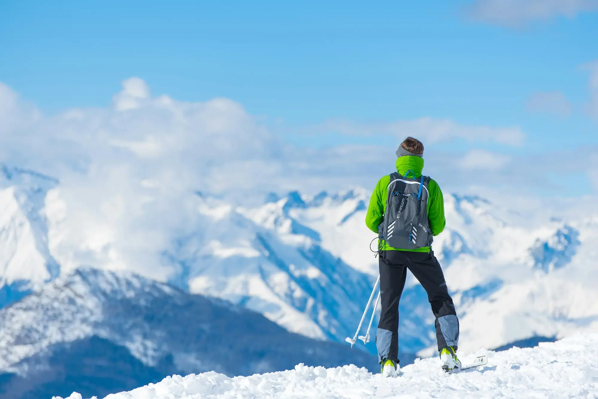 Skitouren Person auf Skiern blickt auf schneebedeckte Berge.