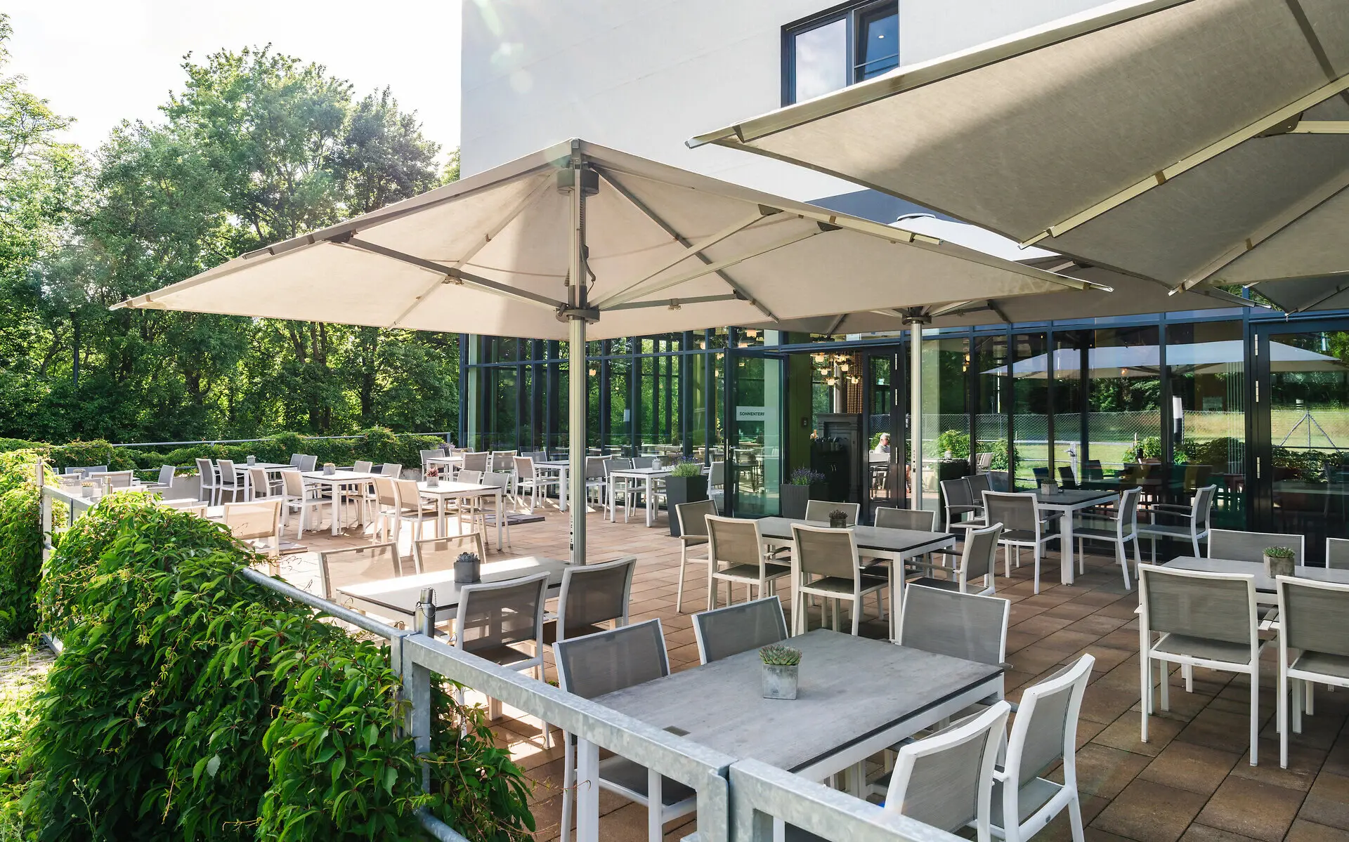Sonnenterrasse Eine Terrasse mit Tischen und Stühlen.