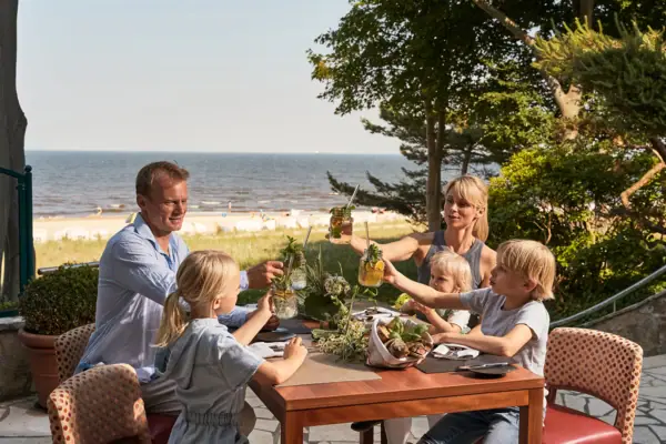 Eine Familie sitzt an einem Tisch mit Getränken im aja Strandhotel Bansin.