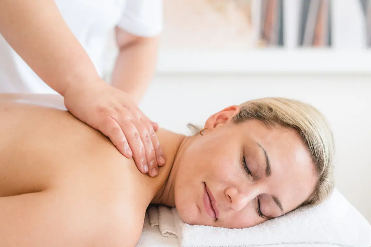 aja SPA Anwendung Eine Frau liegt mit geschlossenen Augen auf einem weißen Handtuch.