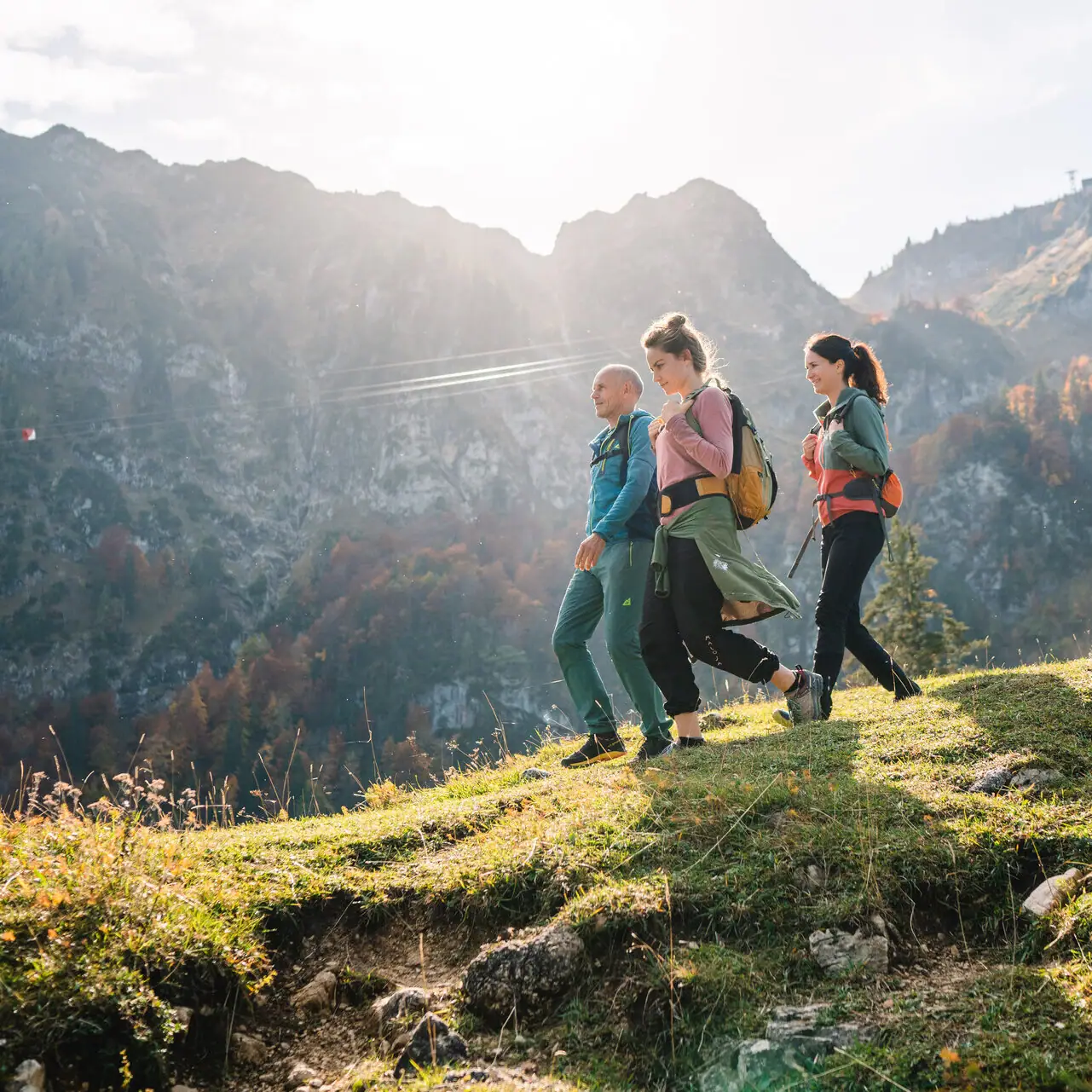 Wandern in Ruhpolding Eine Gruppe von Menschen wandert auf einem Hügel mit Bergen im Hintergrund.