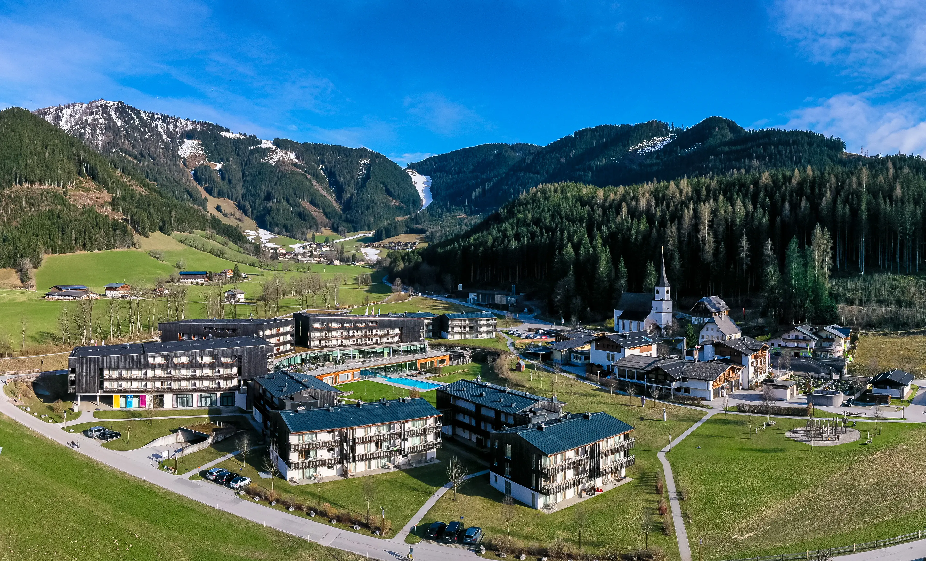 aja Werfenweng Eine Gruppe von Gebäuden in einem Tal mit Bergen im Hintergrund.