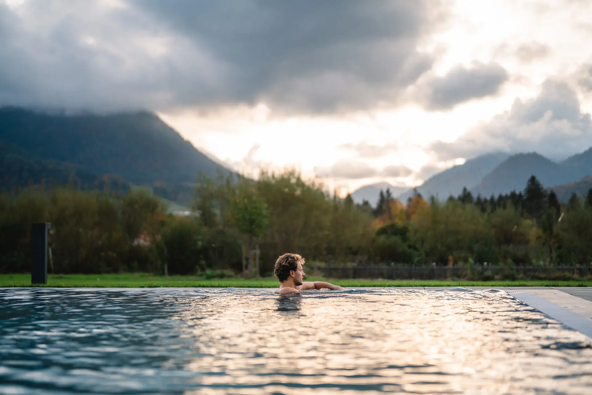 Ein Mann im Pool mit Bergen im Hintergrund.