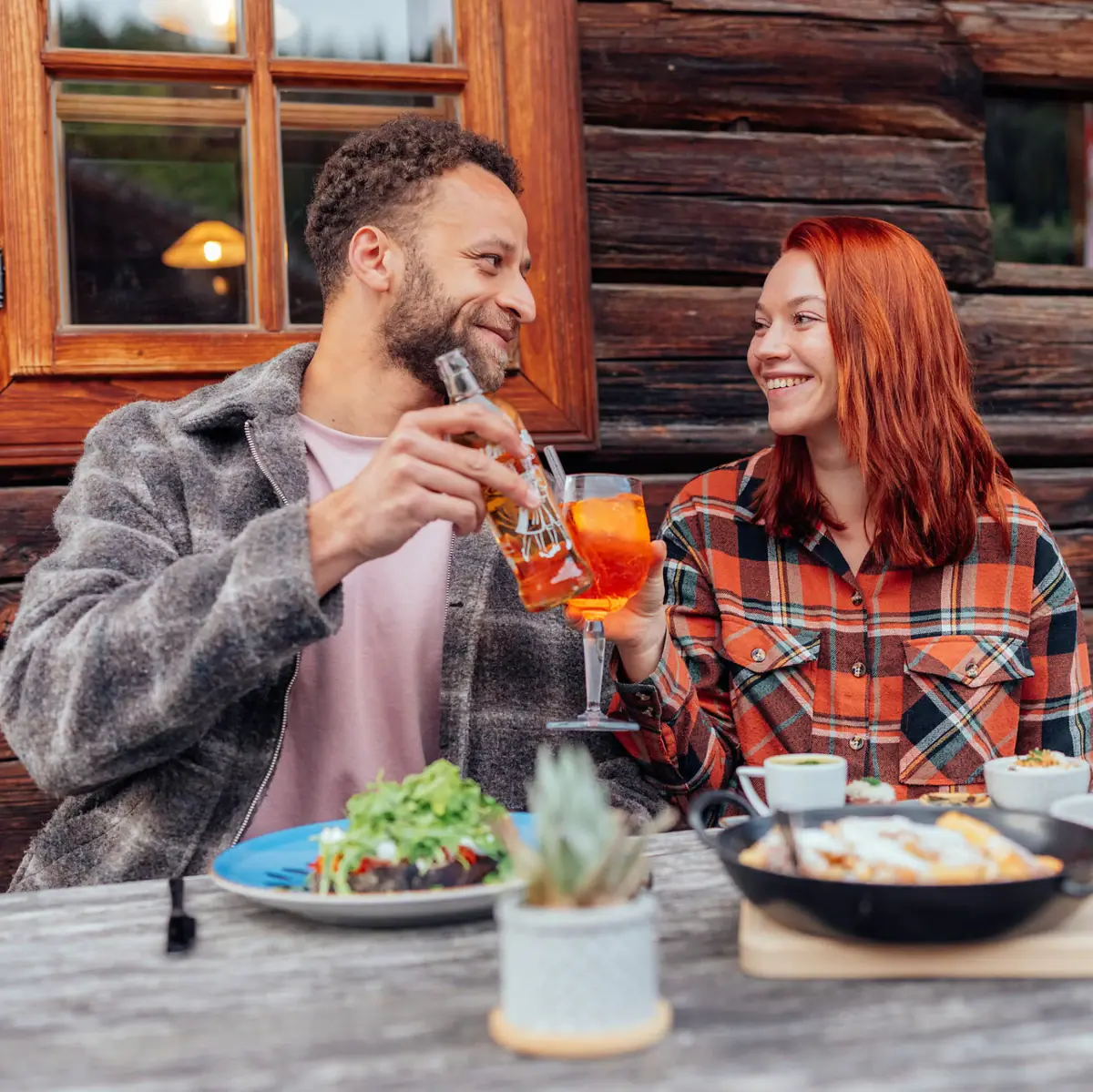 Ein Mann und eine Frau trinken an einem Tisch mit Essen und einer Pfanne.