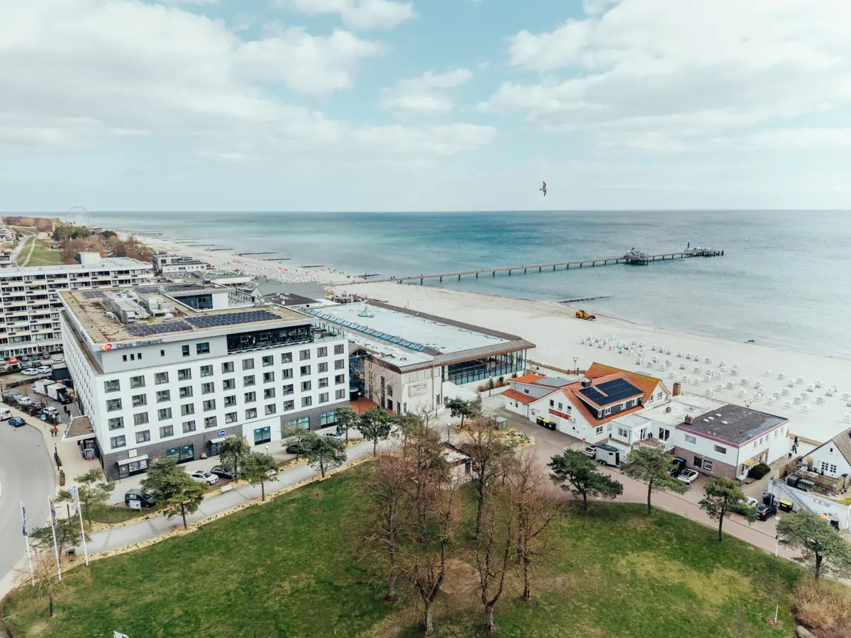 Strand mit Gebäuden und einem Pier im Vordergrund.