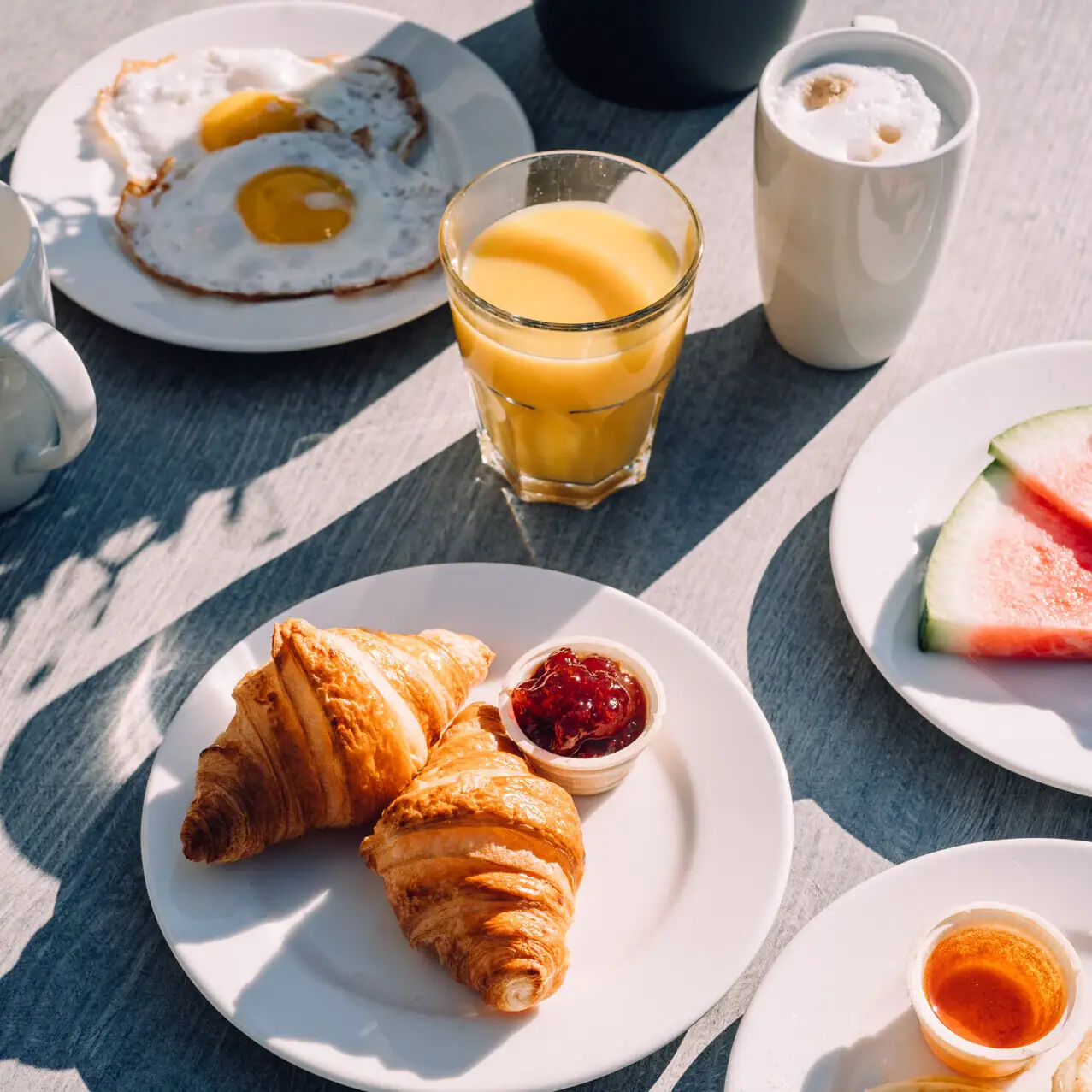 Croissants Ein Tisch mit Tellern voller Speisen und Getränken.