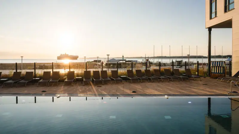 Außenpool Ein Pool mit Stühlen und einem Boot im Hintergrund.