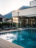 Pool mit Stühlen und einem Gebäude vor einem Berg im Hintergrund in einem Resort.