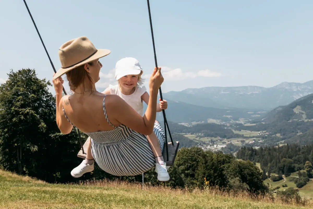 Eine Frau und ein Kind schaukeln im Freien.