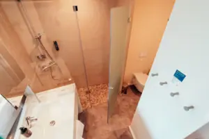 Badezimmer mit Glastür-Dusche und Waschbecken