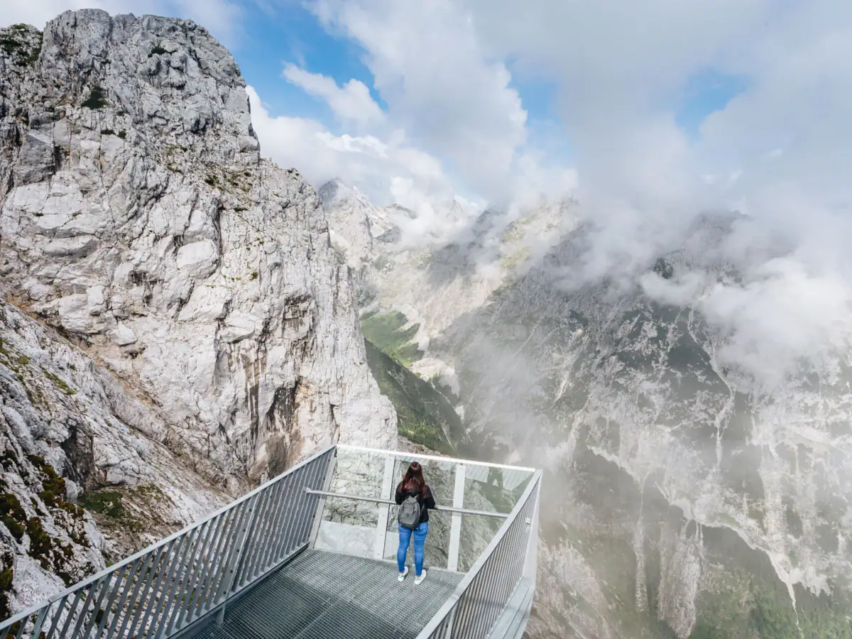 AlpspiX Eine Frau steht auf einer Brücke über einem Berg.