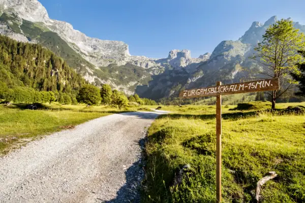 Ein Schild auf einem unbefestigten Weg in einer bergigen Landschaft.