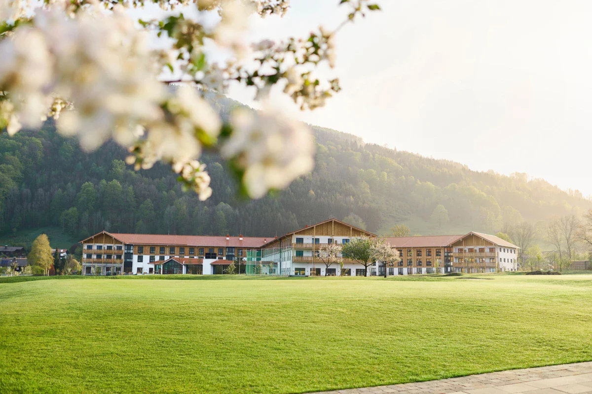 Ein Golfplatz in Ruhpolding mit Gebäuden im Hintergrund.