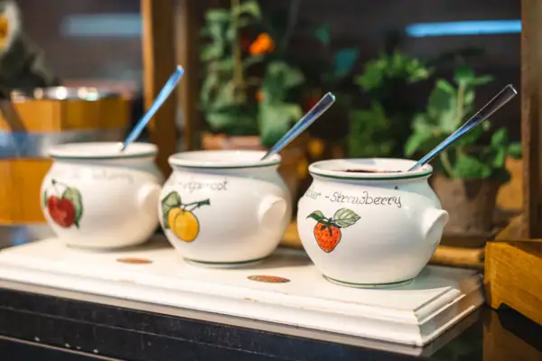 Marmelade Eine Gruppe weißer Töpfe mit Löffeln.