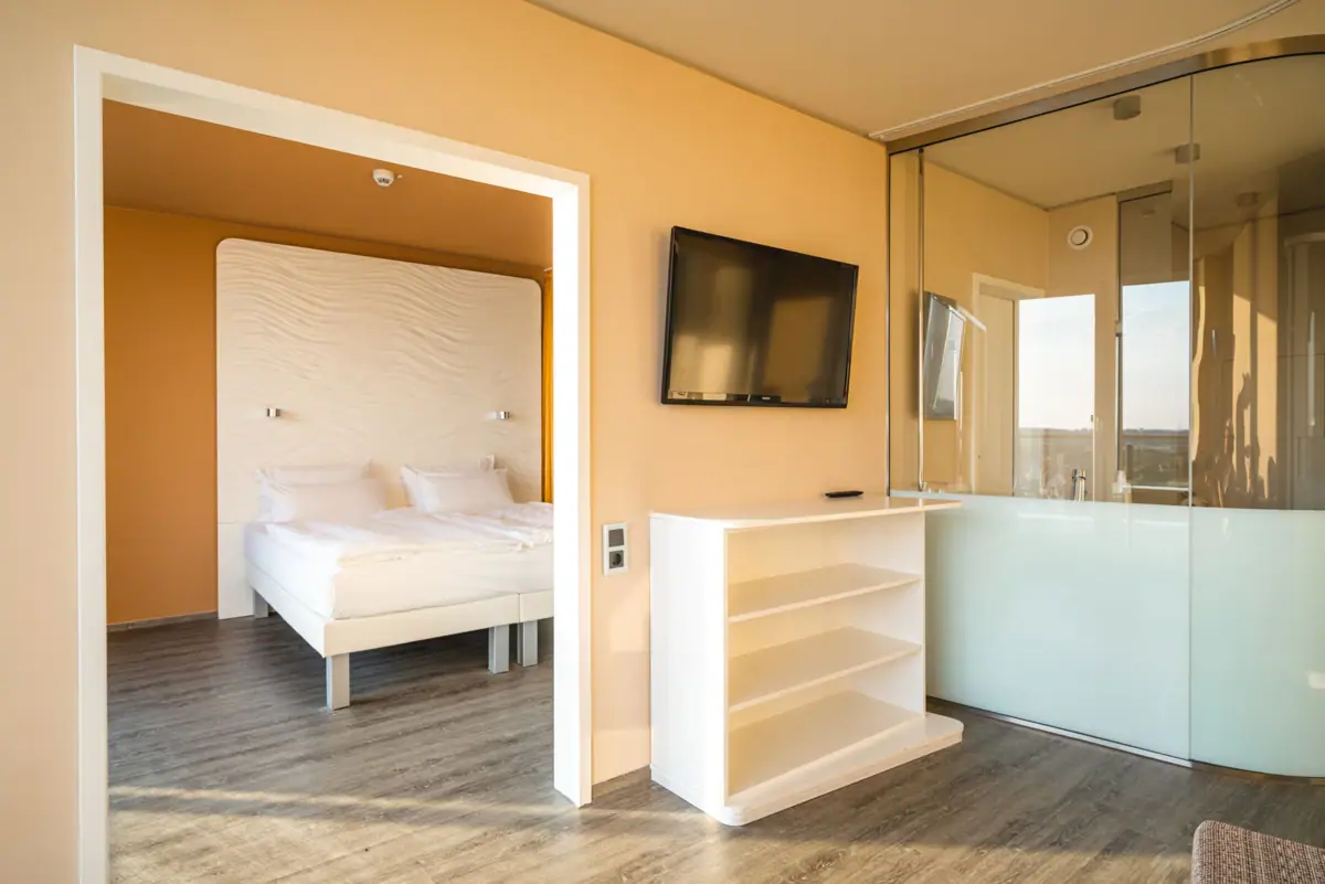 Suite im aja Warnemünde Schlafzimmer mit Bett und Fernseher.