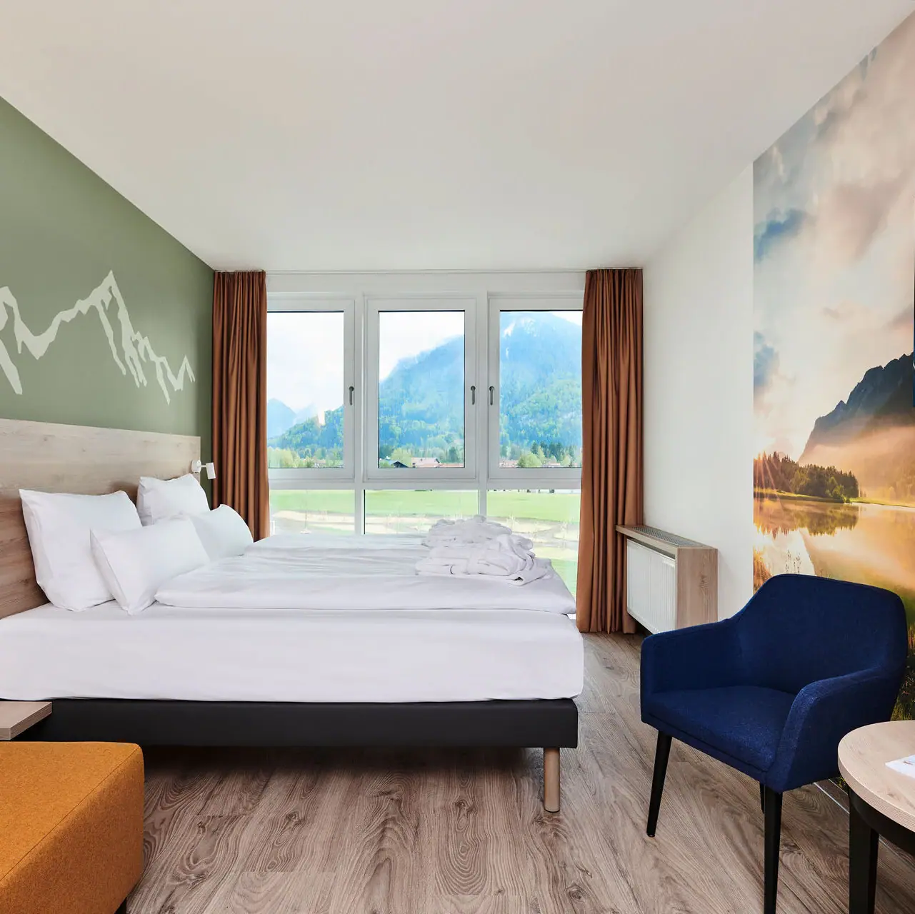 Ein Raum mit einem Bett und Aussicht auf die Berge aus dem Fenster des aja Ruhpolding.