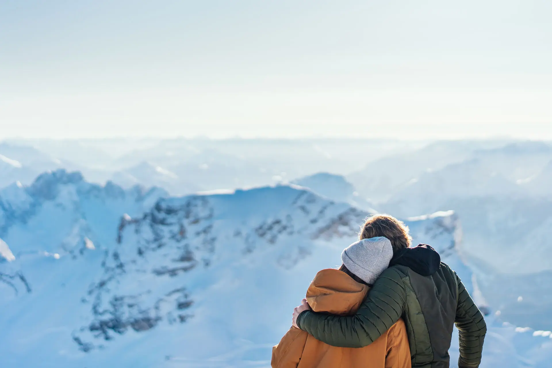 Paar umarmt sich auf einem verschneiten Berg.