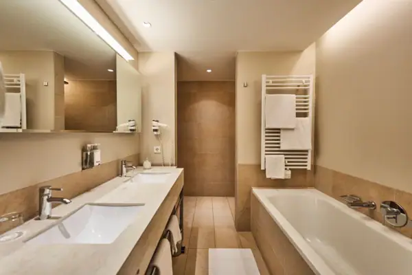 Badezimmer mit Badewanne und Waschbecken, ausgestattet mit Armaturen und Fliesen.