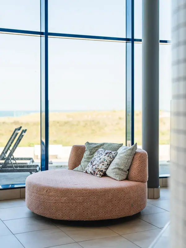 Runde Couch mit Kissen vor einem Fenster.