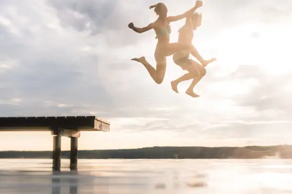 Ein Paar springt von einem Steg ins Wasser.