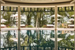Ein Pool mit Sonnenschirmen und Stühlen im Hintergrund.
