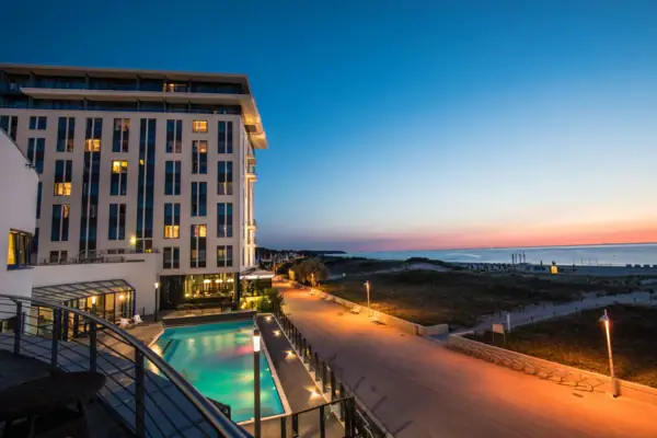 Das Hotel mit dem Außenpool und einem Gehweg entlang der Ostsee.