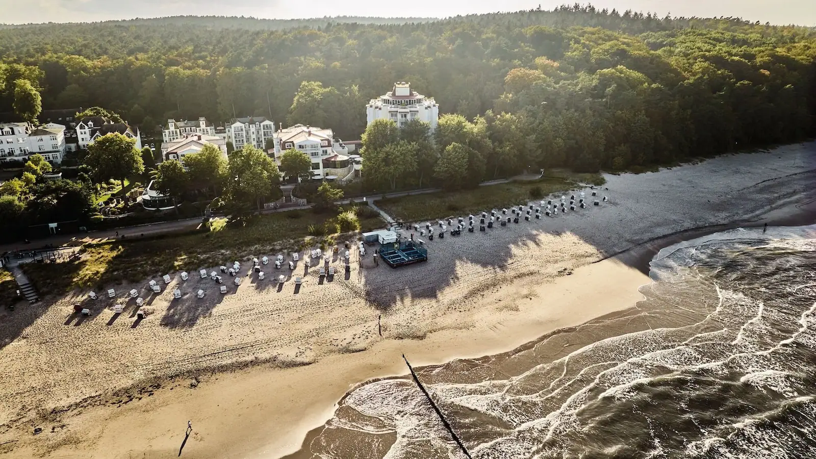Ein Strand mit vielen Strankörben und Bäumen.