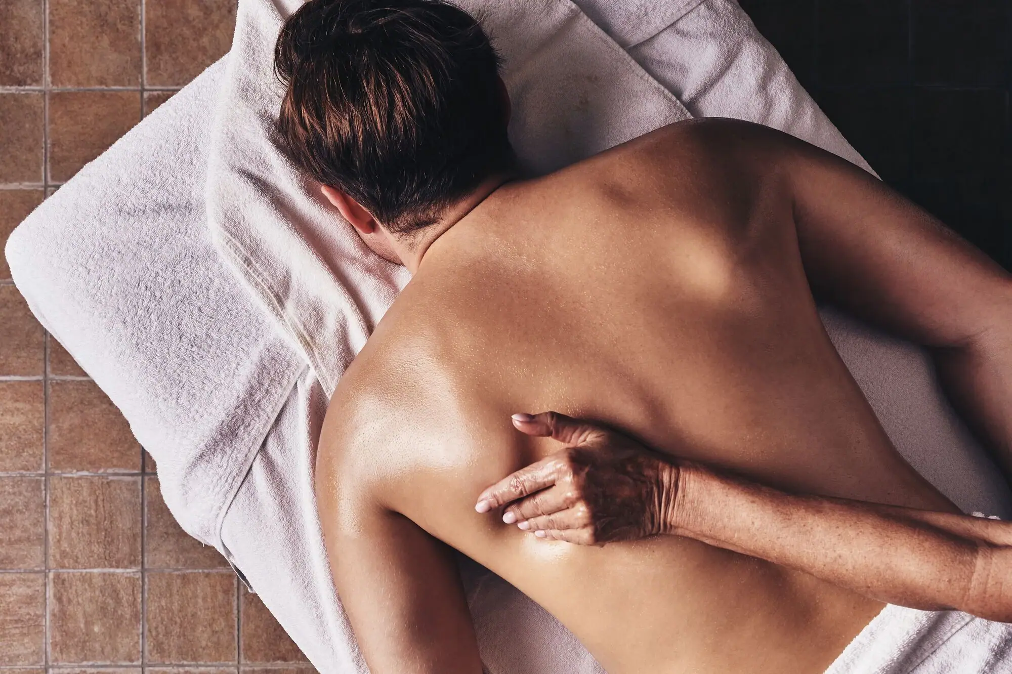 Ganzkörper-Massage Person auf einem Handtuch liegend mit dem Rücken zur Kamera.
