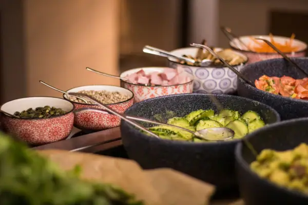 Salatbar im aja Ruhpolding Eine Gruppe von Schüsseln mit verschiedenen Speisen.