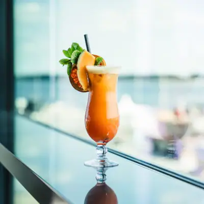 Cocktail Ein Glas mit einem Cocktail und Zitrusgarnitur auf einem Tisch.