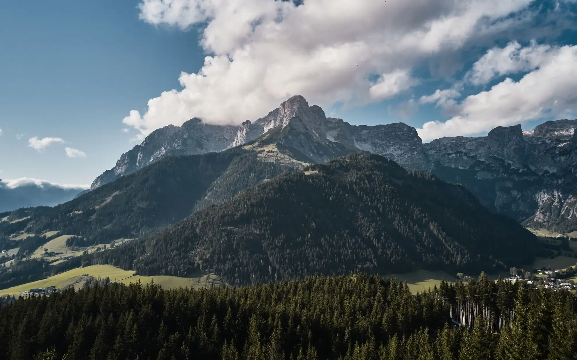 Mountain landscape with trees and clouds.