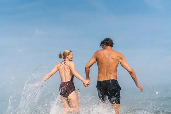 Warnemünde Meer Ein Mann und eine Frau halten sich im Wasser an den Händen.
