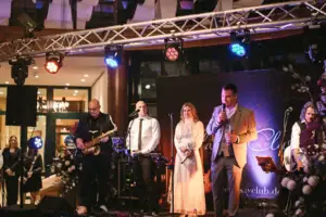 Eine Gruppe von Menschen auf einer Bühne bei einem Konzert mit Musikinstrumenten.