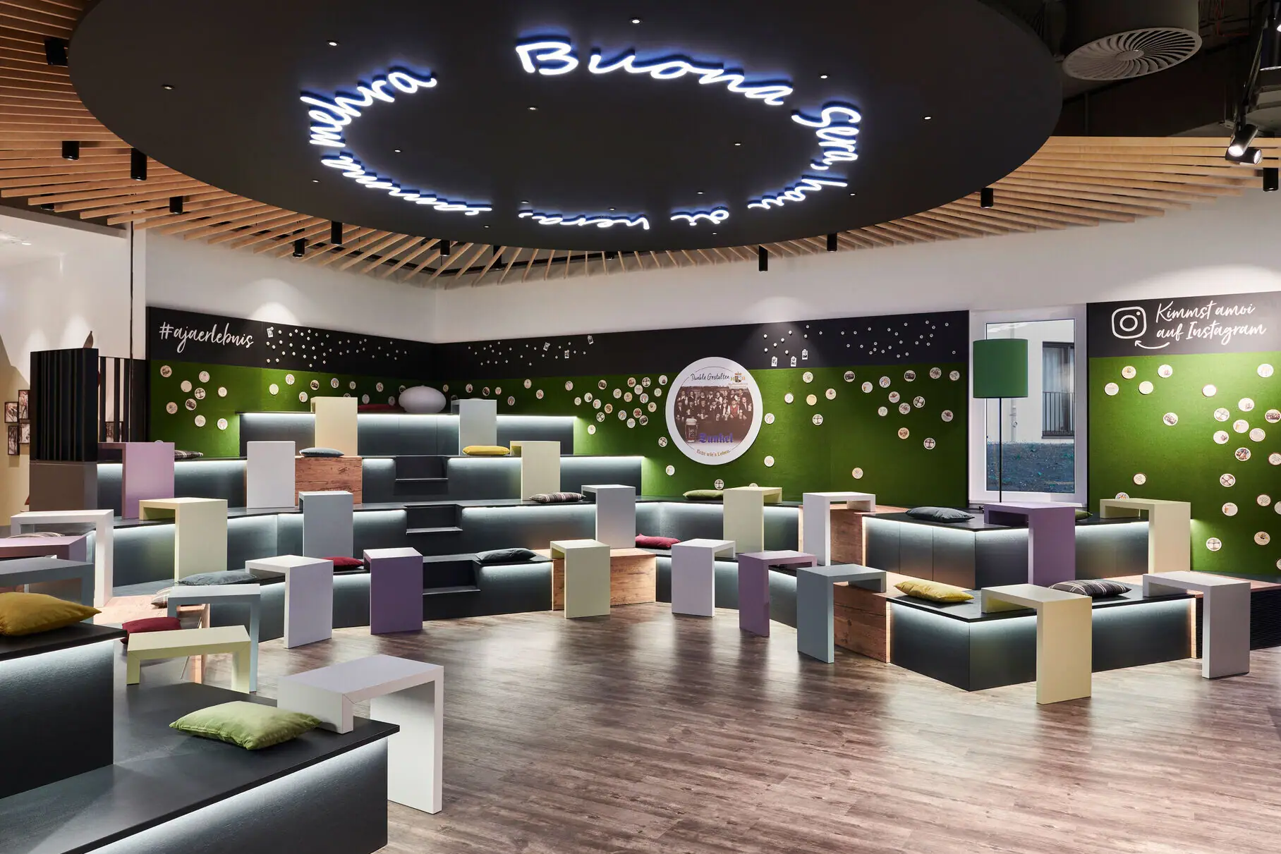 Barbereich im aja Ruhpolding Ein Raum mit vielen bunten Bänken und Tischen.