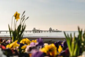 Ein Pier mit einer Brücke in der Ferne, umgeben von Wasser und Himmel.