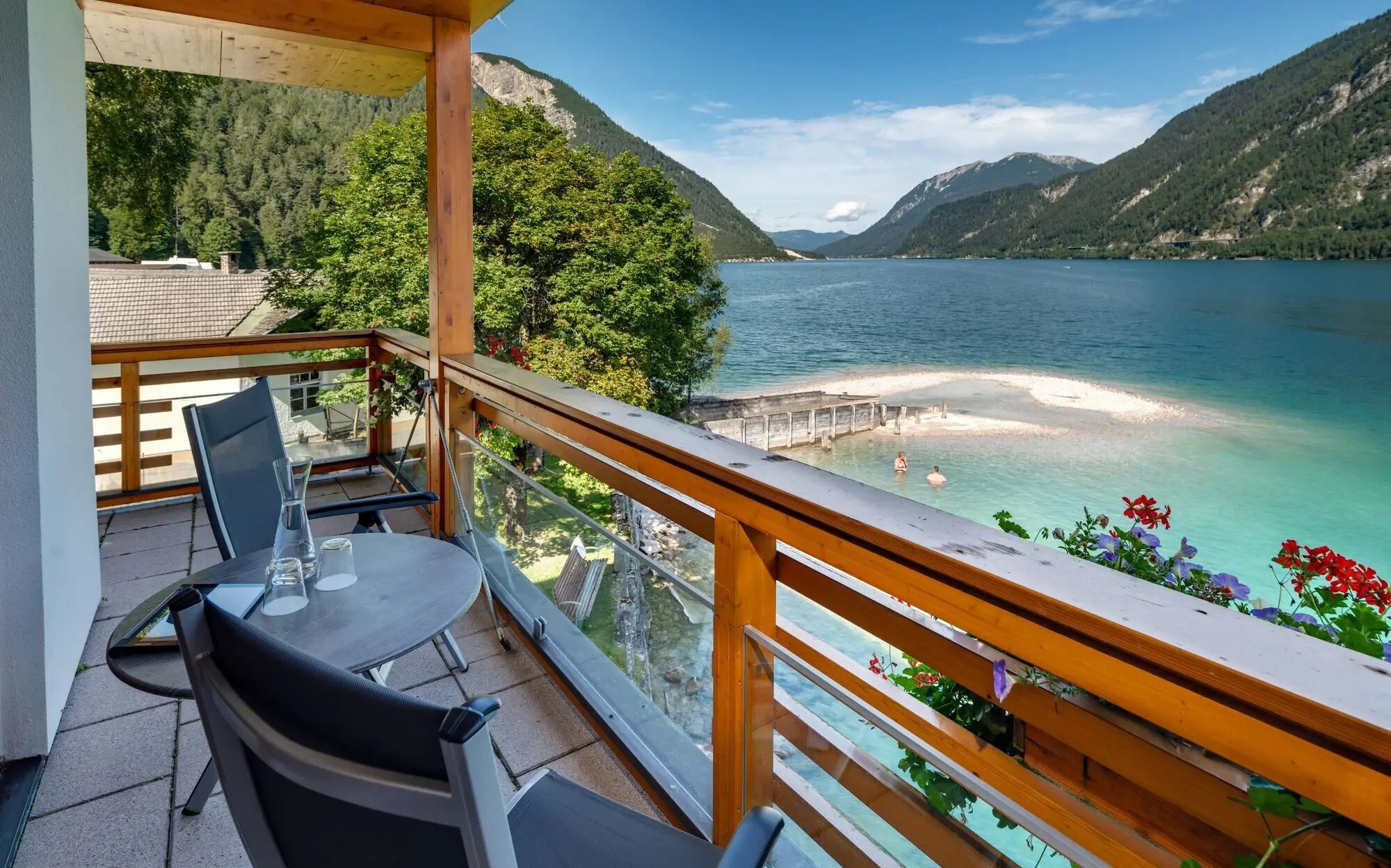 Balkon mit Tisch und Stühlen, der auf ein Gewässer blickt.