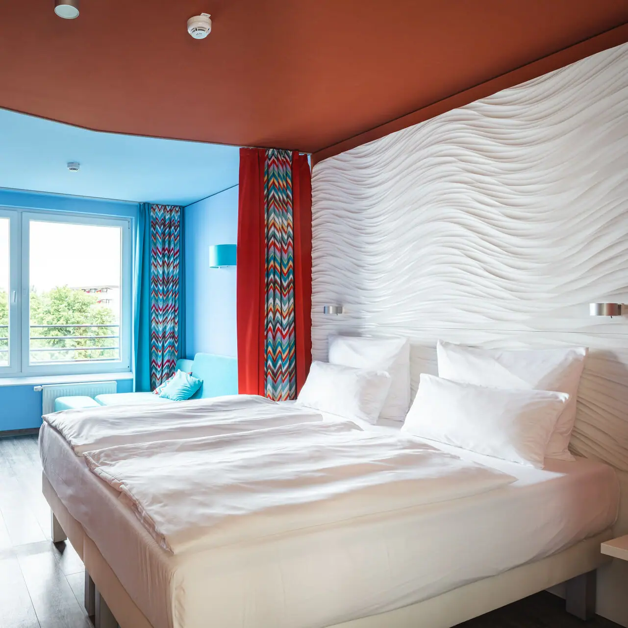 Ein Hotelzimmer mit einem großen Betten und roten Vorhängen.