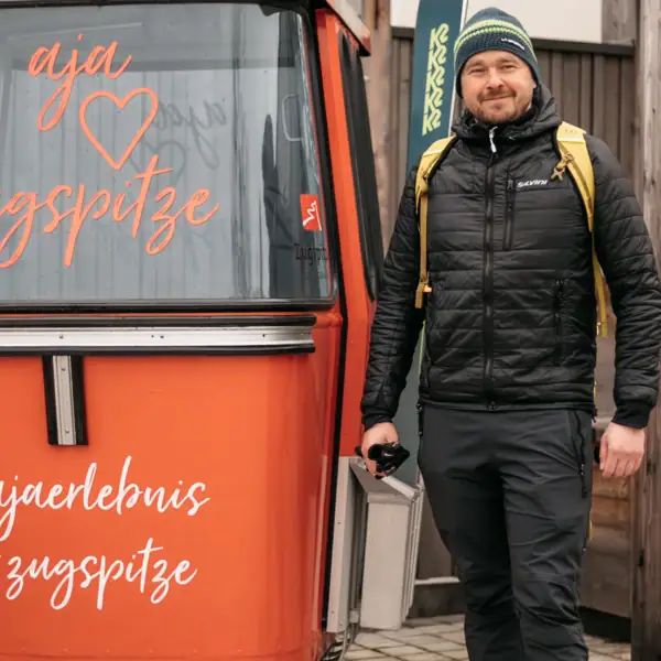 Ein Mann steht neben einem kleinen orangefarbenen Container.